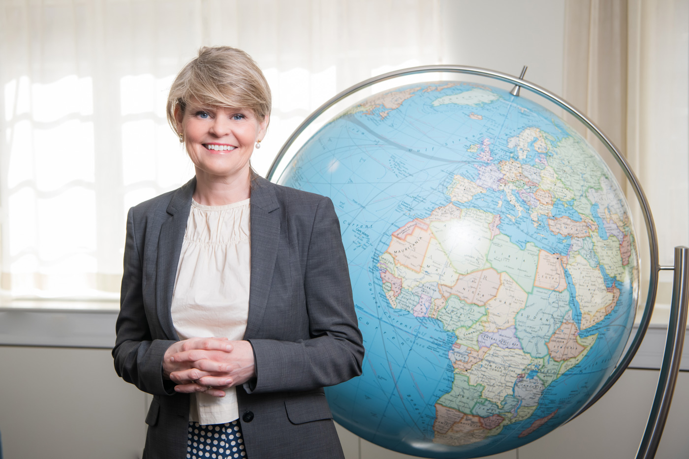 Lena Bertilsson in front of a terrestrial globe.