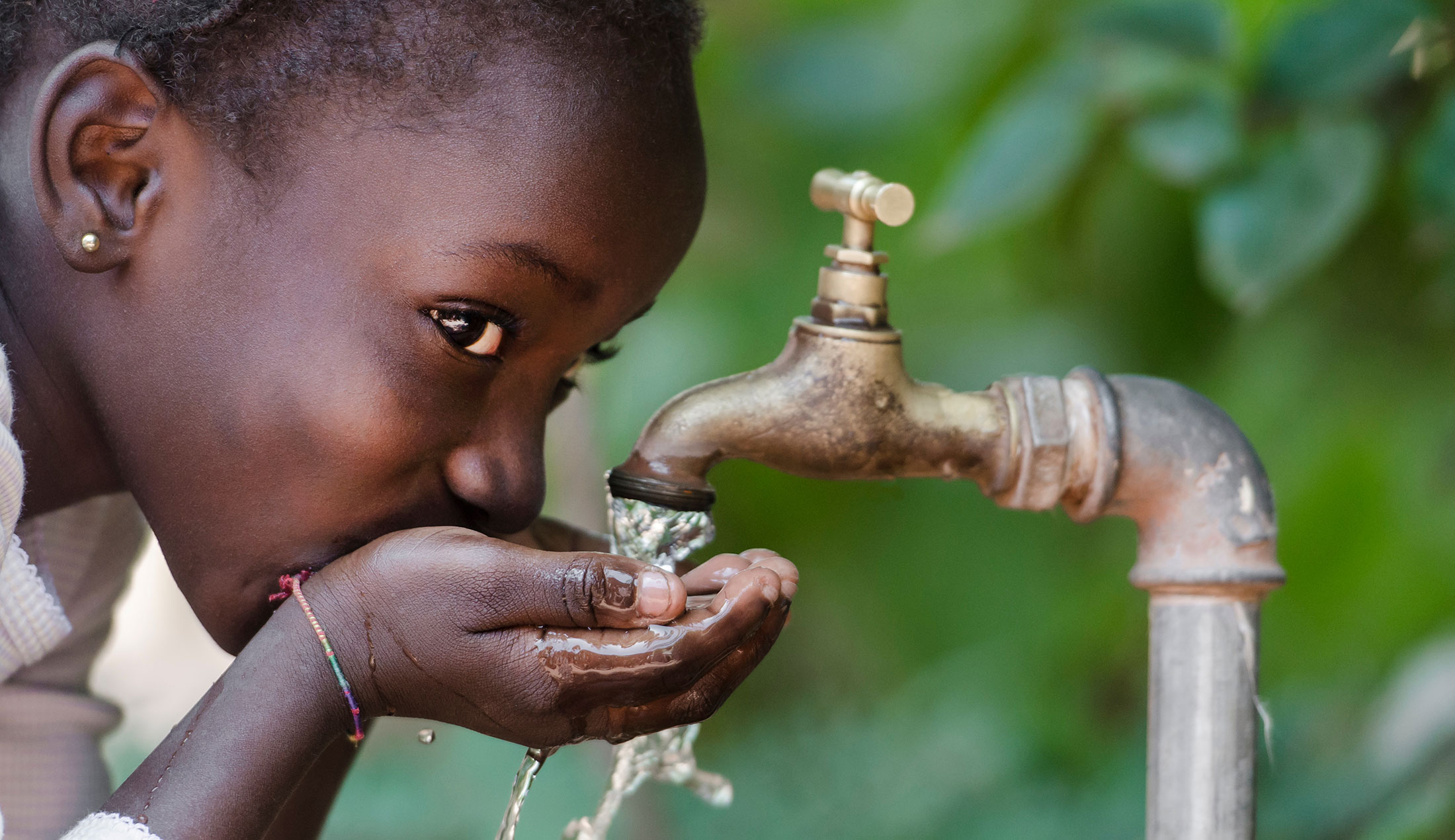 Child in Africa drinking water from a tap