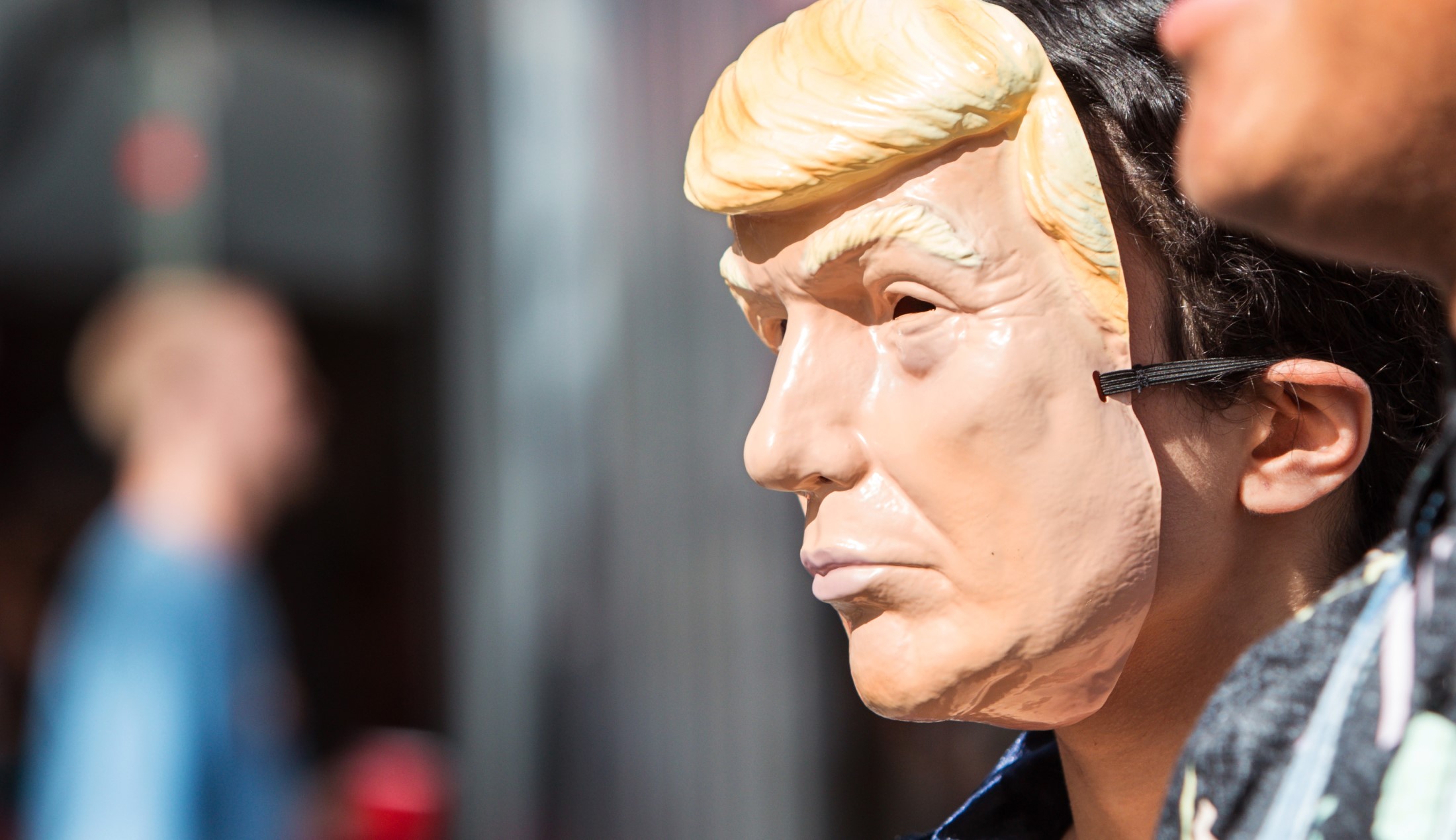 En person bär en ansiktsmask som ser ut som Donald Trump