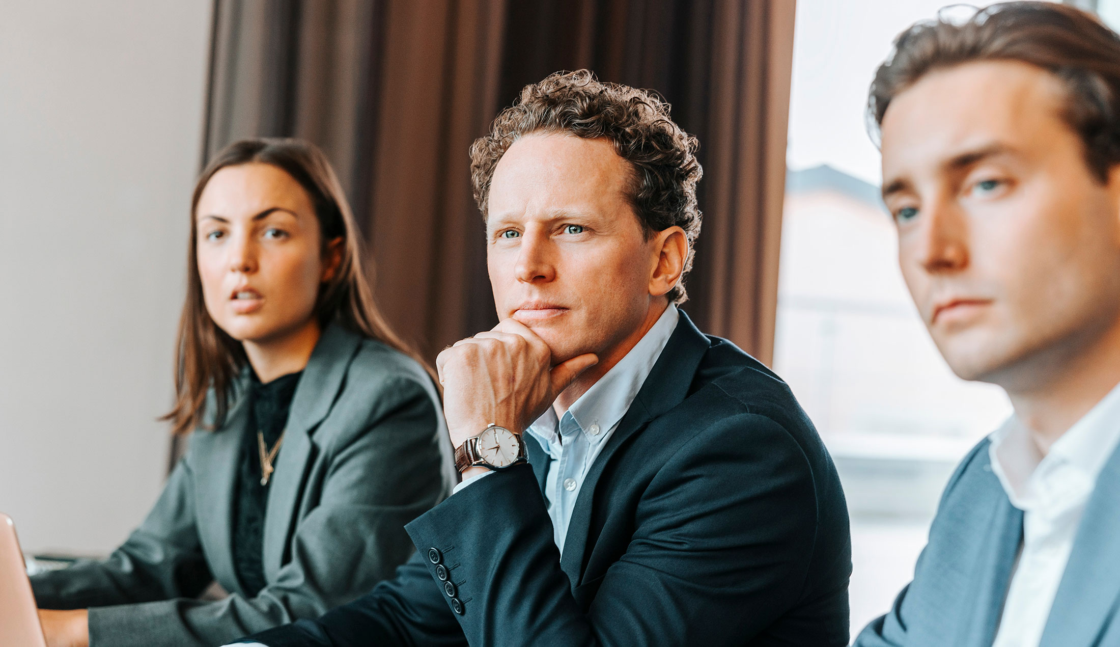 A woman and two men are seated at a conference table.