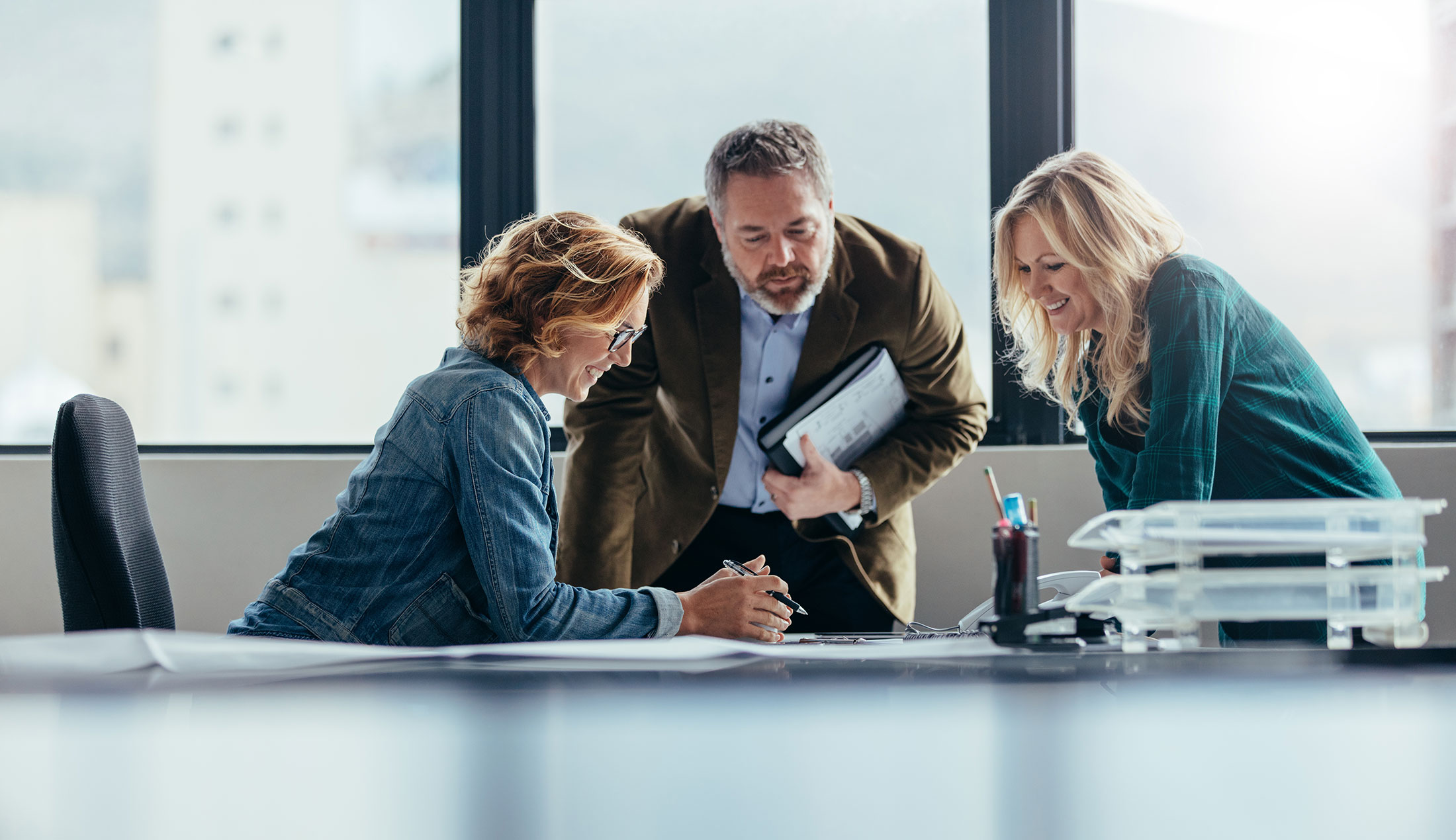 Two women and a man working together at a table.
